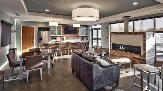 Charlotte Square Community Room — modern lounge with leather sofa, kitchen bar, and fireplace